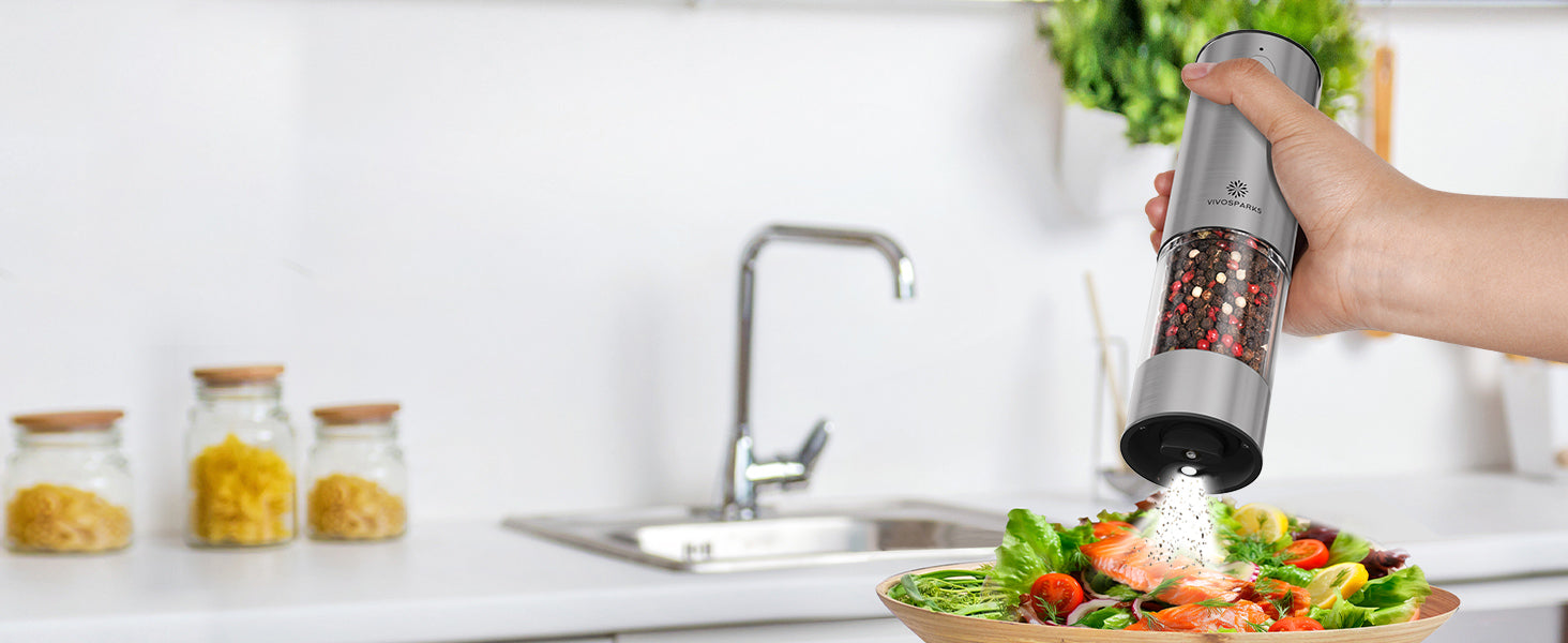 Person using a pepper grinder over a salad in a kitchen setting