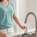 Person holding a water filter under a kitchen faucet.
